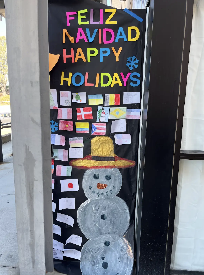 Spanish teacher Yanire Cercet-Martinez's door is decorated with various country flags. The door included the words 'Feliz Navidad' in colorful letters, which translates to 'Happy Holidays' in English.